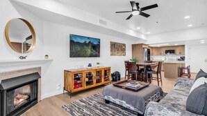 A modern living room with a fireplace, a dining area, and a kitchen.