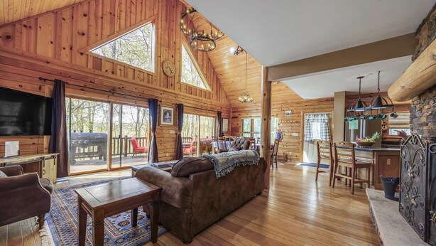 Une cabane spacieuse dotée d’un grand espace de vie, de planchers en bois et d’une cuisine agrémentée d’éléments en pierre.