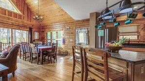 L’intérieur d’une cabane en bois comprend un coin repas, une cuisine et de grandes fenêtres.