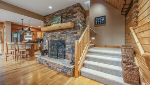 Une cuisine moderne avec une cheminée en pierre, un plancher en bois et un escalier menant à une mezzanine.