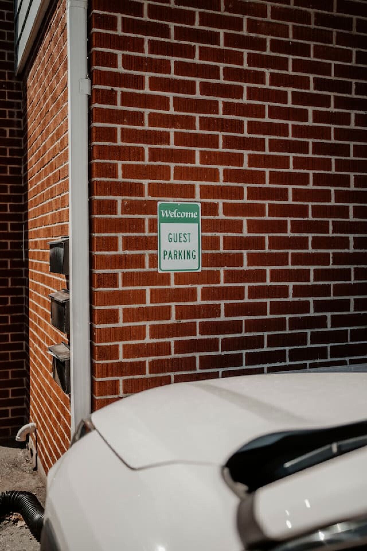Un muro de ladrillo con un letrero que dice 'Welcome Guest Parking'.