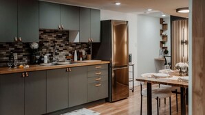 Een moderne keuken met donkere kastjes, een roestvrijstalen koelkast en een houten eettafel gedekt voor twee personen.