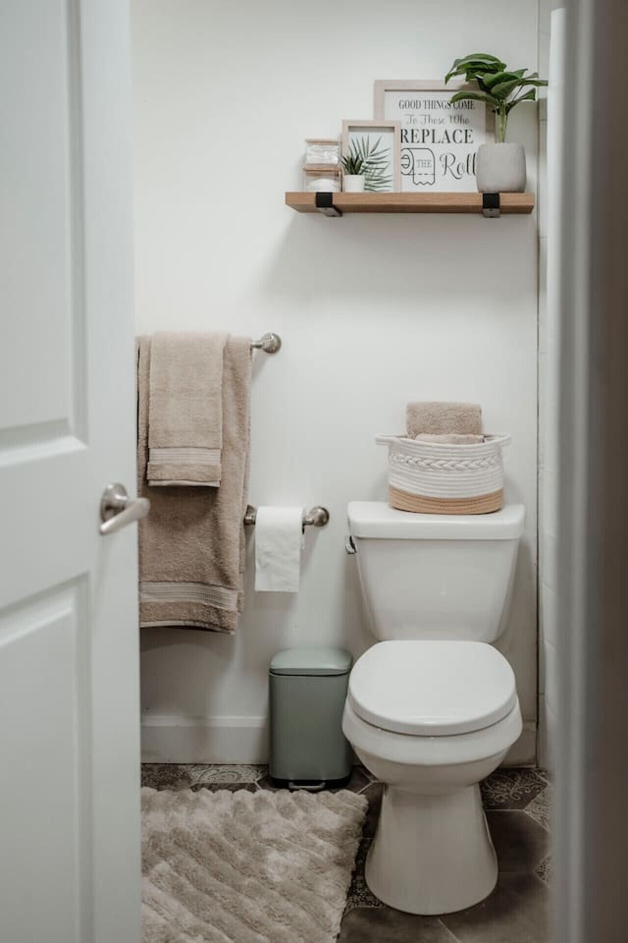 Ein kleines, sauberes Badezimmer mit Toilette, Mülleimer und Handtuchhalter.