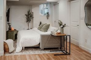 Een slaapkamer met een bed, nachtkastje en een klein raam.