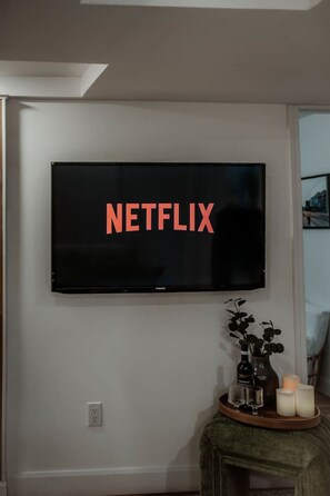 Een aan de muur bevestigde televisie met het woord 'NETFLIX' op het scherm.