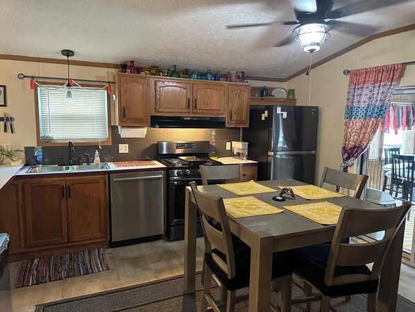 A kitchen with wooden cabinets, a stainless steel refrigerator, a stove, and a dining table with chairs.