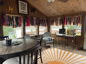 Un interior de madera con techo alto, un letrero enmarcado, telas de colores y vistas al exterior.