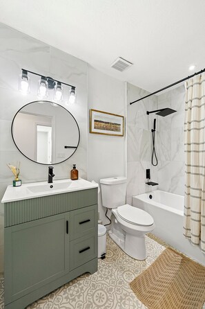 A modern bathroom with a vanity, toilet, and bathtub.