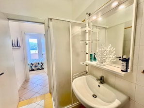 A modern bathroom with a white sink, a large mirror, and a shower area.