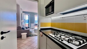 A modern kitchen with a gas stove, a microwave, and a view to the living area. - La Pianotta suite with seaview (Porto Azzurro)