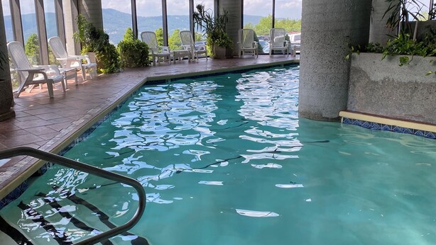 An indoor swimming pool with clear water, surrounded by large windows offering a view of the mountains. - Charming 2-bedroom condo with fitness room and WiFi in fabulous Sugar Mountain (Sugar Mountain)