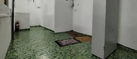 A room with green patterned flooring, white walls, a ceiling fan, and a door.