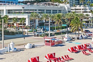 A beachside hotel with a pool, beach chairs, and umbrellas.