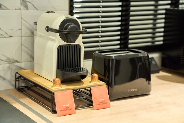 A kitchen area with a coffee machine, a toaster, and two signs indicating the availability of red fruits.