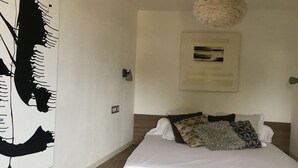 A bedroom with a bed, a chair, a wall art piece, and a ceiling light fixture. - Cosy village house (Peynier)