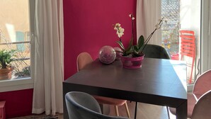 A dining area with a table, chairs, a hanging light fixture, and a window with curtains. - Cosy village house (Peynier)