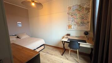 A bedroom with a bed, desk, chair, and a map on the wall.