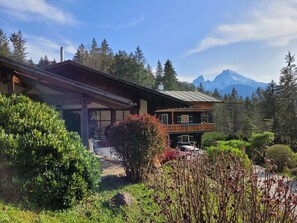 Een chalet met een houten gevel, een balkon en uitzicht op een bergketen.