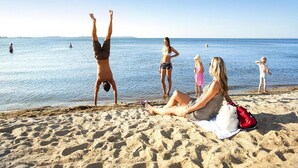Une scène de plage où l’on voit des gens se détendre et une personne faisant la verticale.