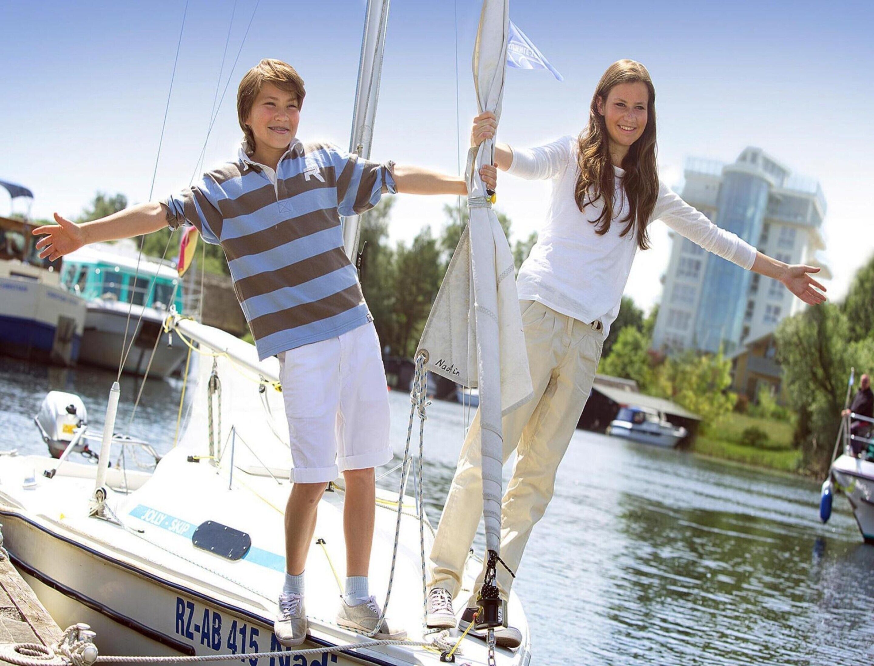 Two people standing on a boat with a cityscape in the background.