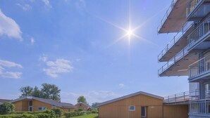 Un bâtiment moderne doté d’un toit plat, d’une vaste zone herbeuse et dégagée, et surplombant un ciel dégagé.