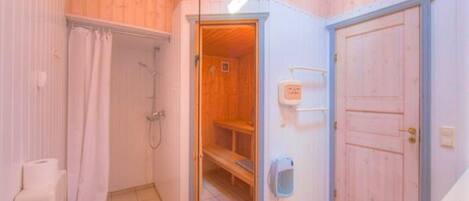 Une salle de bain avec douche, toilettes et un espace sauna en bois.