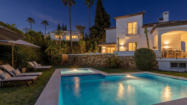 A two-story house with a swimming pool, stone walls, and palm trees. - Villa Birkin by Vacation Marbella (Nueva Andalucía)