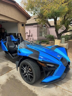 A blue sports car parked in front of a house with a garage.