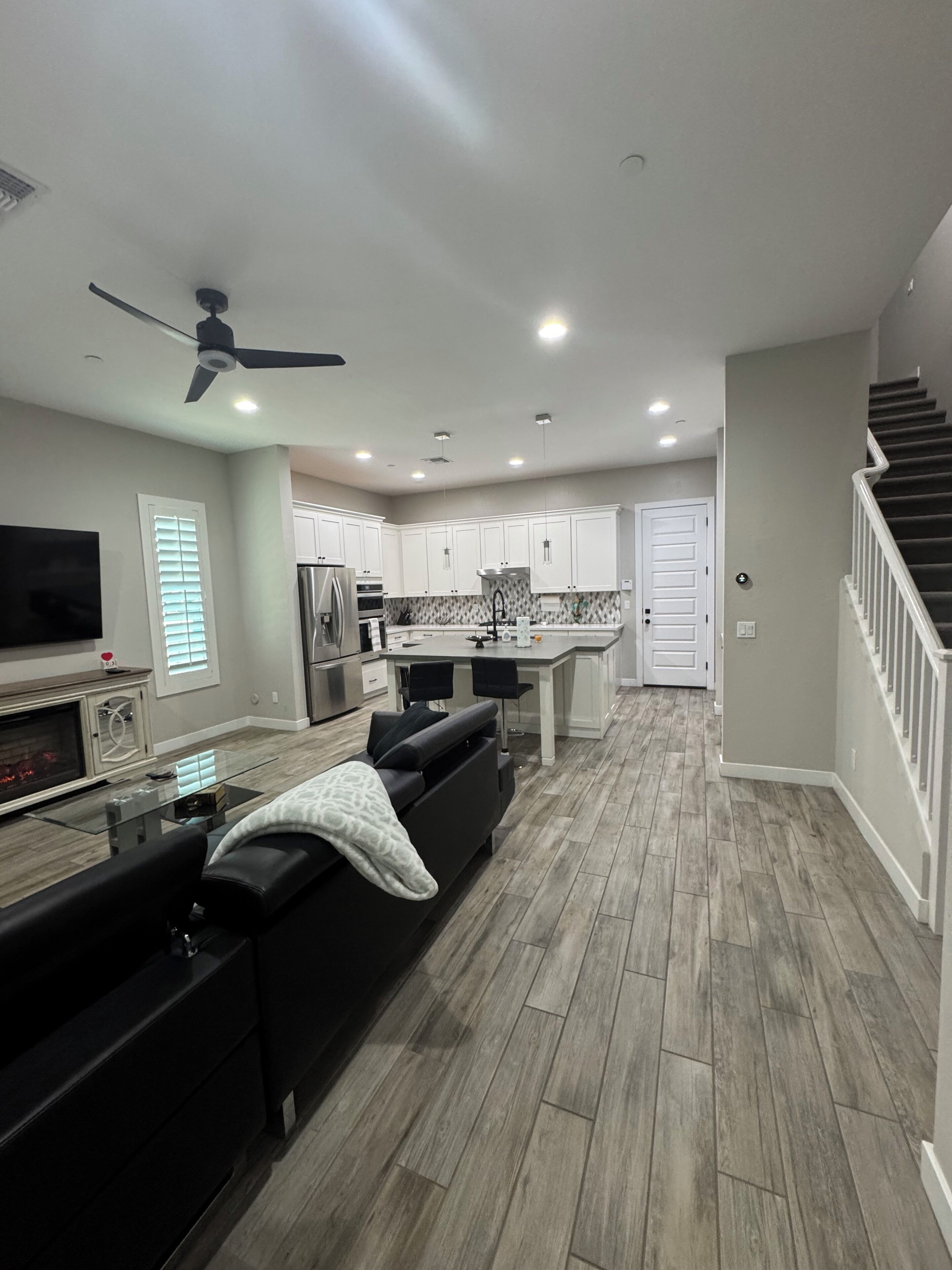 A modern kitchen with white cabinets, a central island, and a built-in oven.