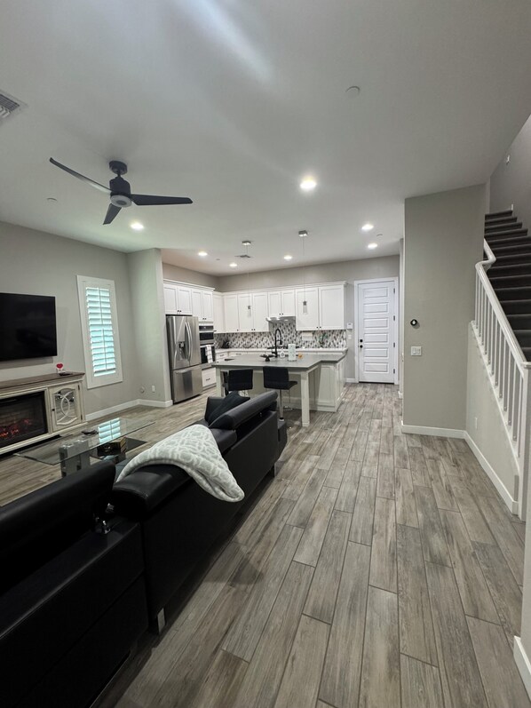 A modern kitchen with white cabinets, a central island, and a built-in oven.