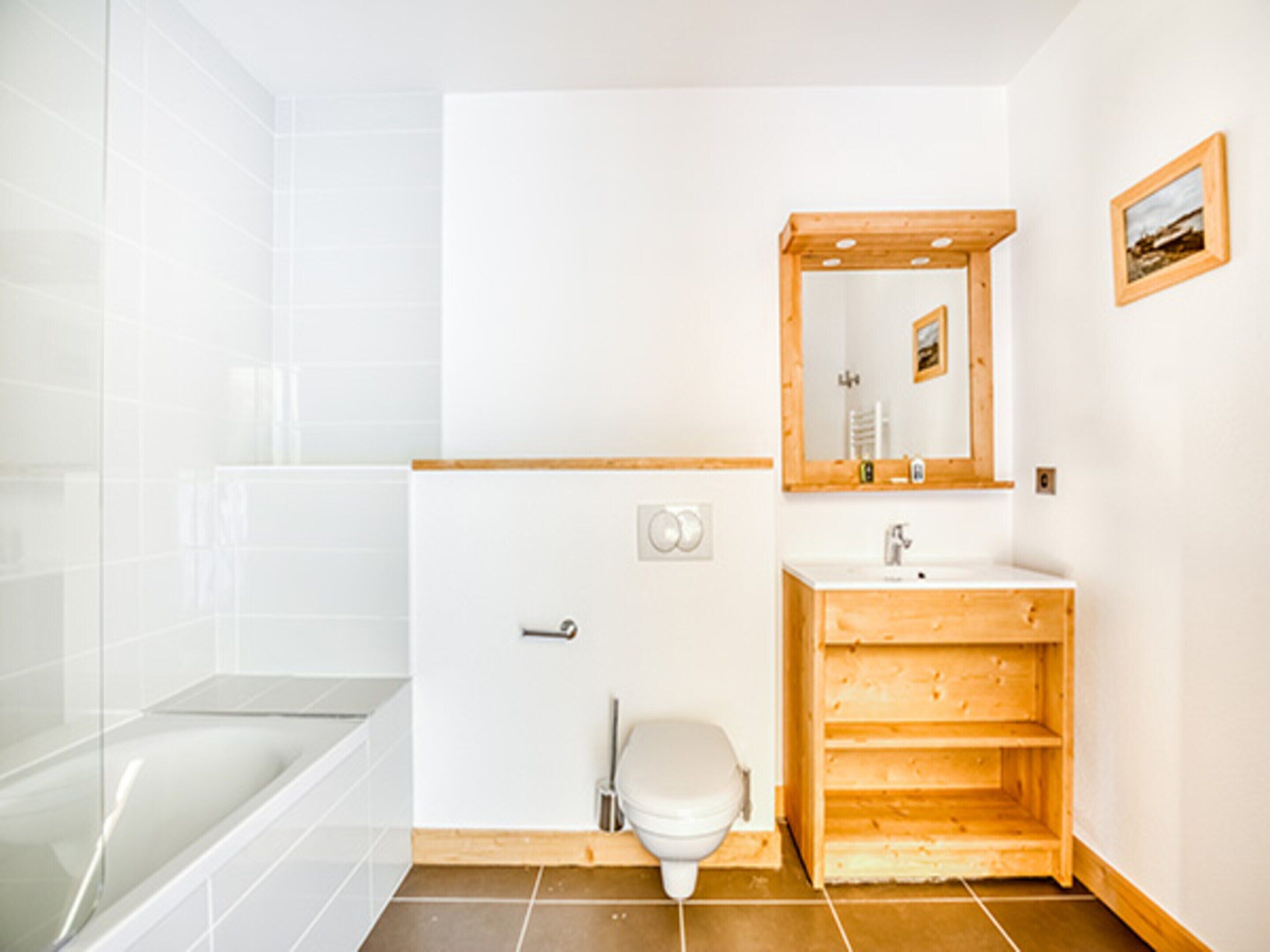 A bathroom with a glass shower enclosure, a wooden vanity with a mirror, and a white toilet.