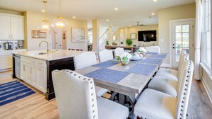 Una cocina amplia con una isla grande, muebles blancos y un tapete azul.