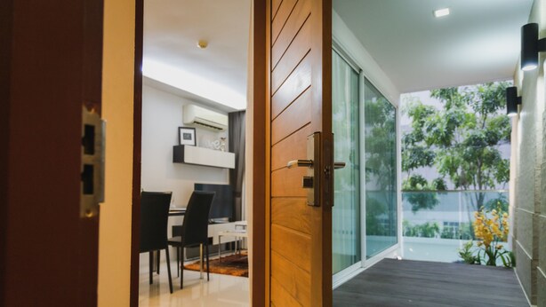 Un interior moderno con una puerta de madera que da a un balcón con vistas a zonas verdes.