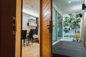 A modern interior with a wooden door leading to a balcony with a view of greenery.