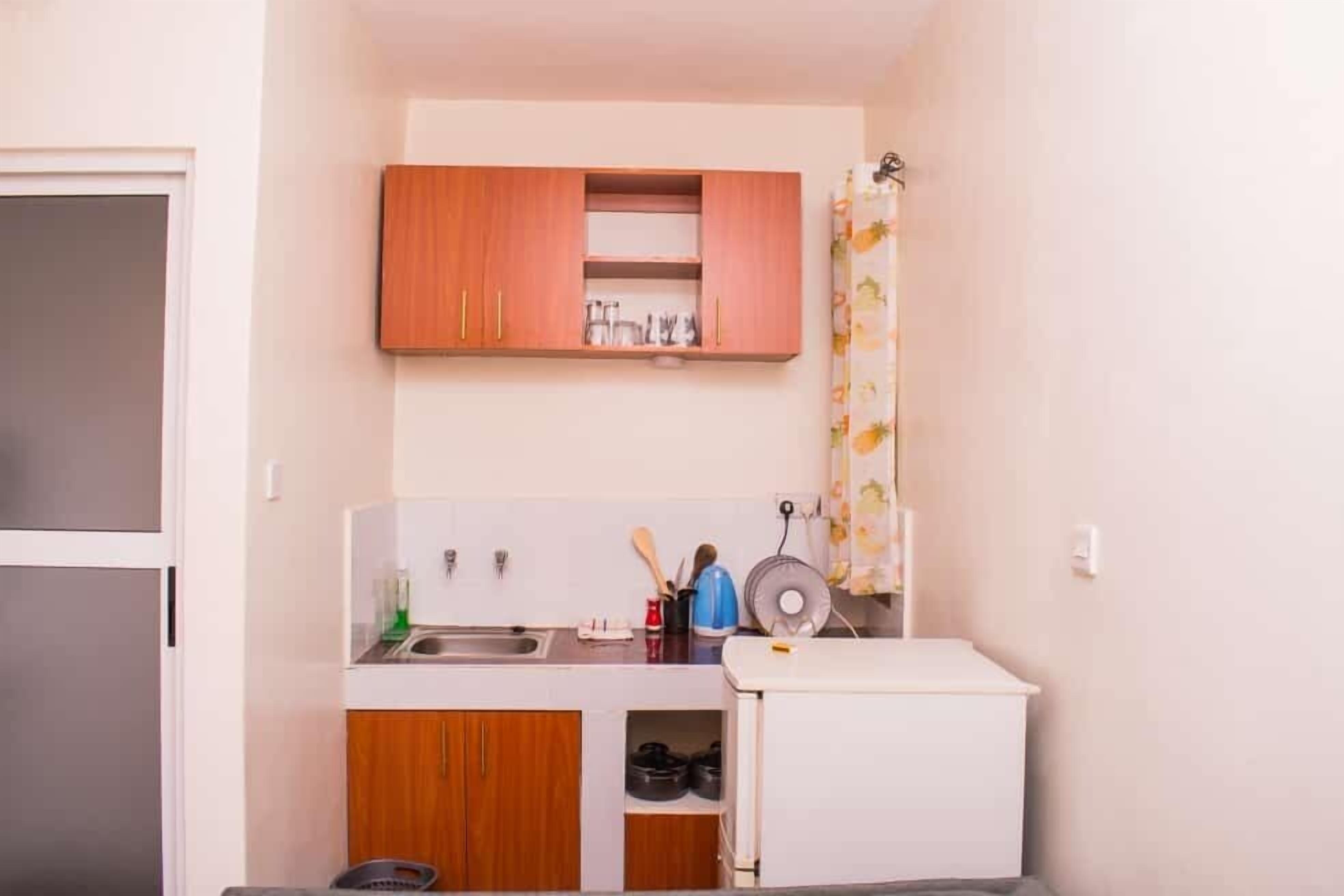 A compact kitchen with wooden cabinets, a sink, and a small refrigerator.
