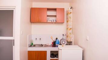A compact kitchen with wooden cabinets, a sink, and a small refrigerator.