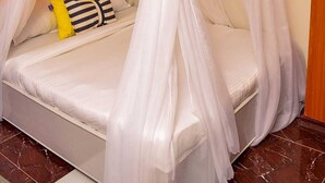 Ein Bett mit Baldachin, Kissen und einem gestreiften Zierkissen.
