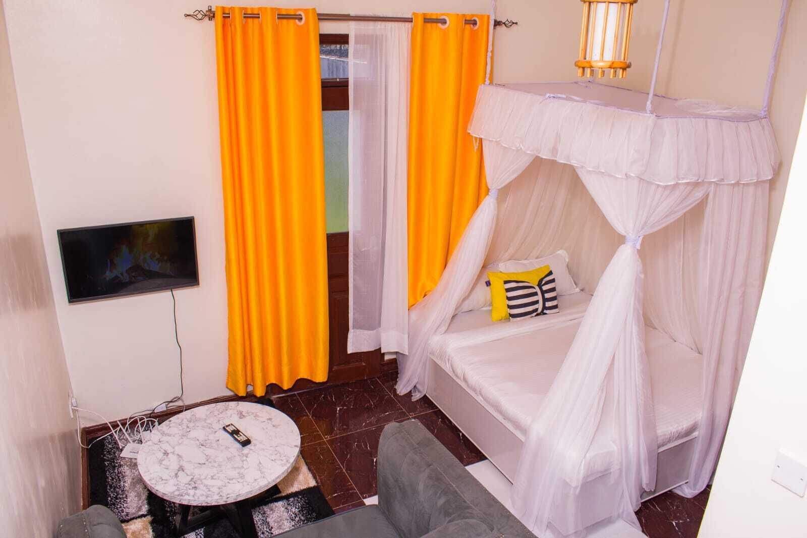 A room with a bed, a TV, a round table, and a chair.
