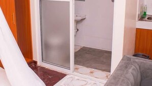 Ein Zimmer mit einer Schiebetür zu einem Badezimmer, einem grauen Sofa und einem Holzschrank.
