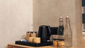 Una encimera de cocina con una cafetera, tazas y frascos de galletas.