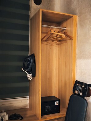A wooden wardrobe with a hanging rack, a black speaker, and a small black box on the floor.