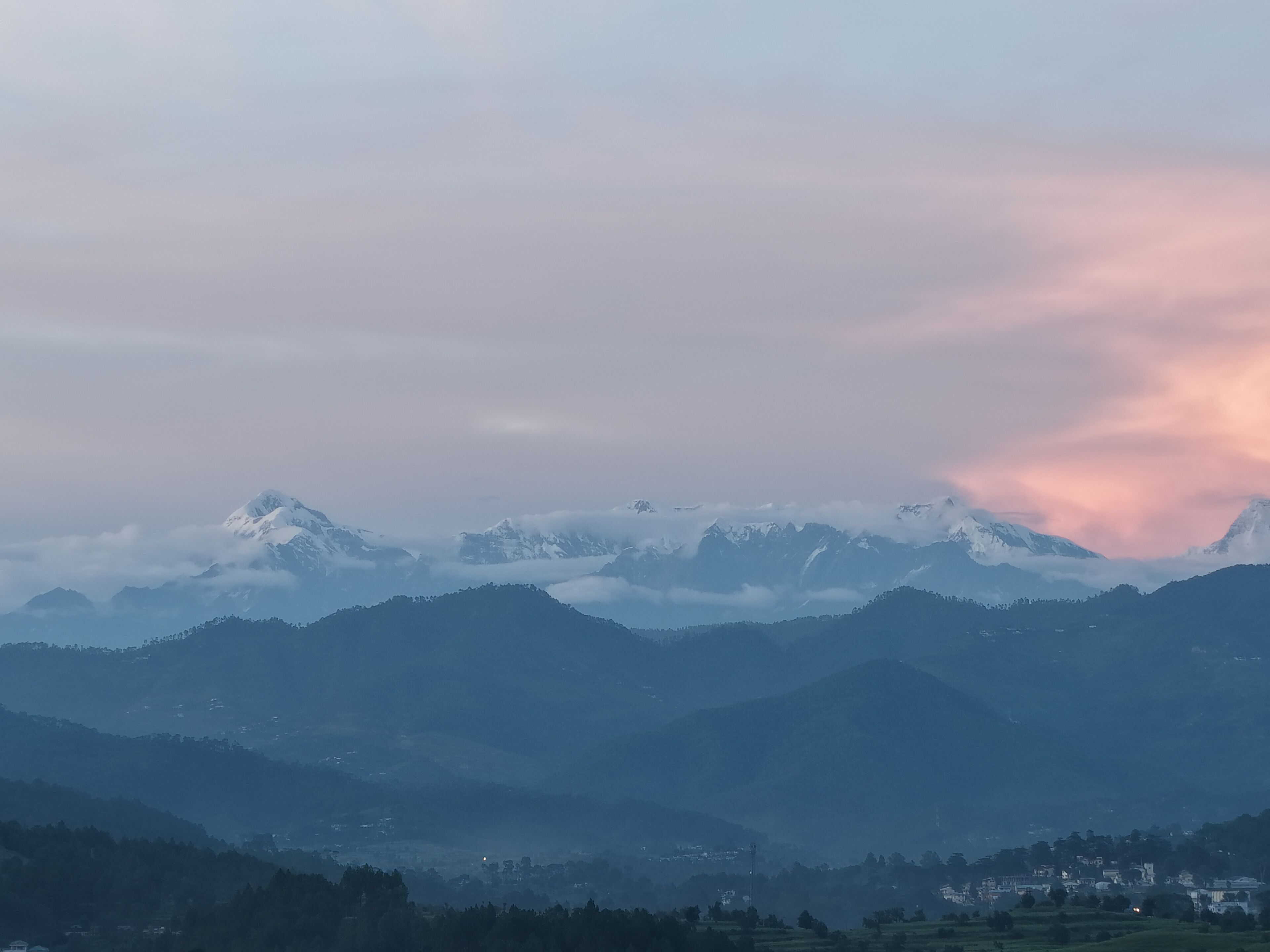 A mountainous landscape with snow-capped peaks and a town in the valley below.
