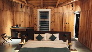 Ein Zimmer mit Holzwänden, einem Bett, Nachttischen, einem Sessel und einem Fenster.