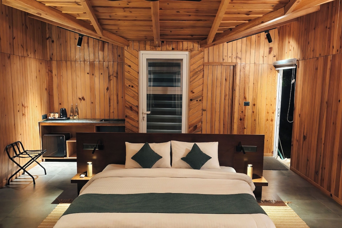 Una habitación con paneles de madera, una cama, mesitas de noche, una silla y un ventanal.