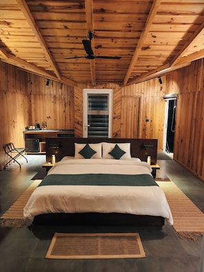 Una habitación con paneles de madera, una cama, mesitas de noche, una silla y un ventanal.