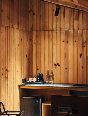 A wooden interior with a kitchen area, including a coffee machine, two bottles, and a toaster.