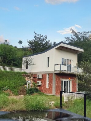A two-story building with a flat roof, a balcony on the upper floor, and a brick facade.