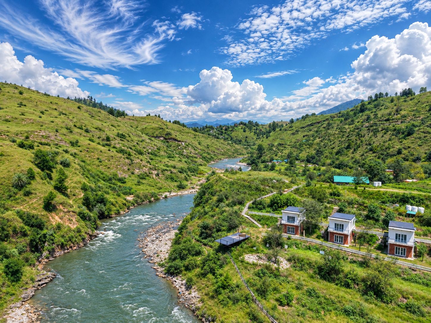 Un río serpentea por un valle verde con casas y un puente.