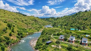 Un río serpentea por un valle verde con casas y un puente.