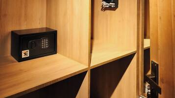 A wooden storage unit with a black safe and a small black object on the top shelf.